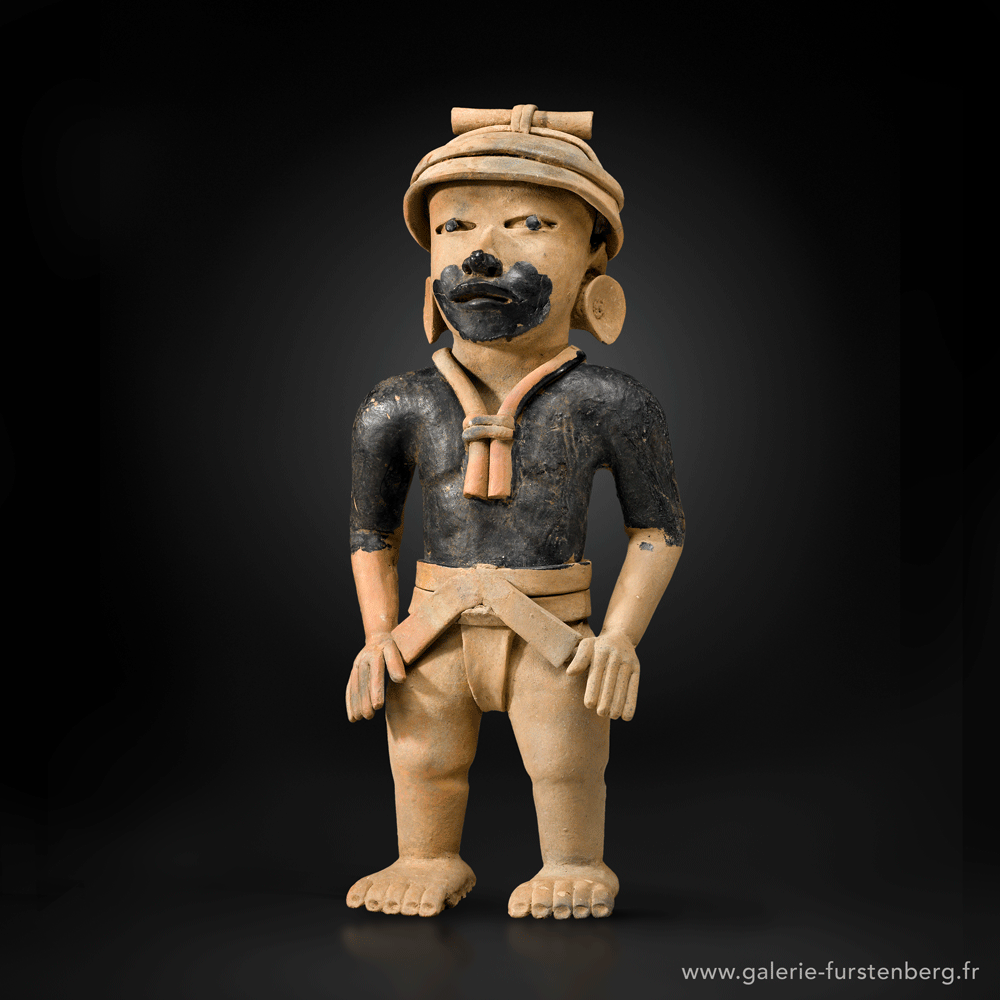 STANDING DIGNITARY WITH HELMET Ochre beige terracotta with natural black tar Mexico, Veracruz culture, 500-900 AD Height: 56,5 cm